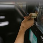 From above of crop anonymous client paying in cash for taxi trip to ethnic driver after arrival