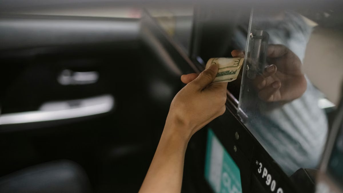 From above of crop anonymous client paying in cash for taxi trip to ethnic driver after arrival